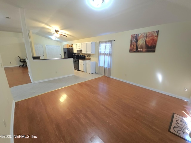 unfurnished living room featuring light wood-type flooring, visible vents, baseboards, ceiling fan, and vaulted ceiling