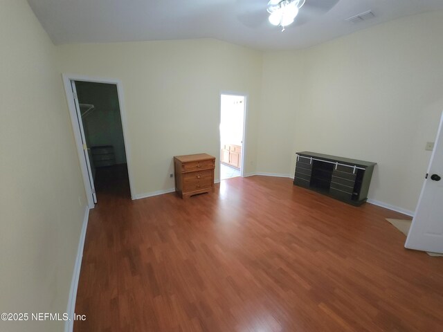 unfurnished bedroom with baseboards, lofted ceiling, wood finished floors, and a spacious closet