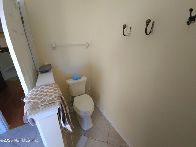 bathroom with baseboards, toilet, and tile patterned flooring