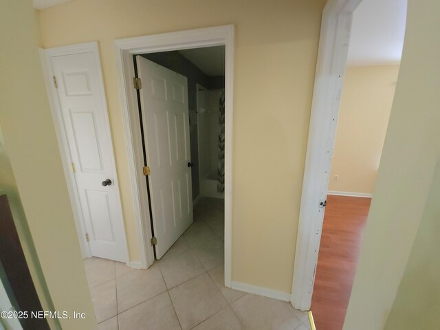 hallway featuring light tile patterned floors and baseboards