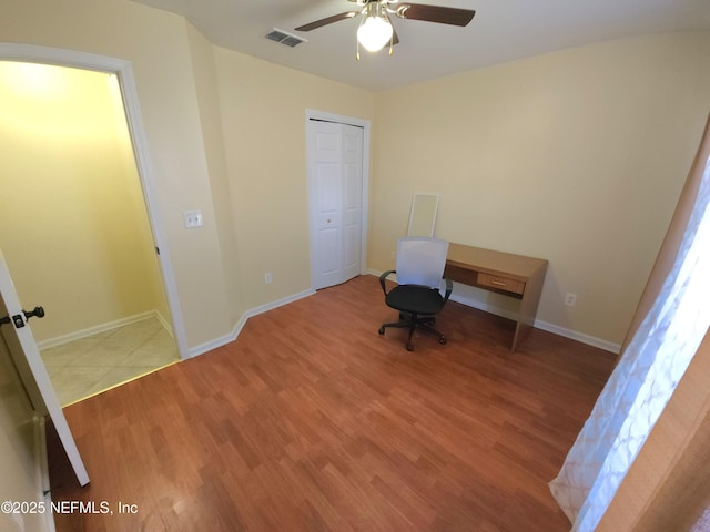 unfurnished office with visible vents, baseboards, wood finished floors, and a ceiling fan