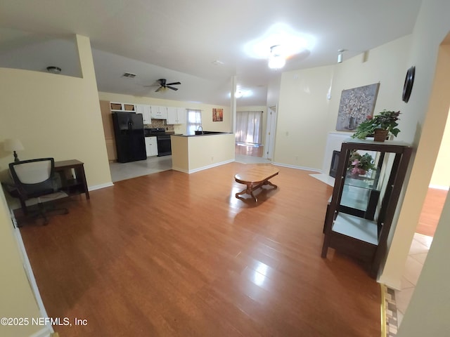 living room featuring visible vents, baseboards, light wood-style floors, and a ceiling fan