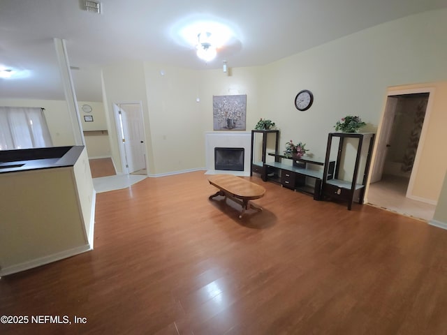 living area with visible vents, baseboards, light wood-style floors, and a fireplace