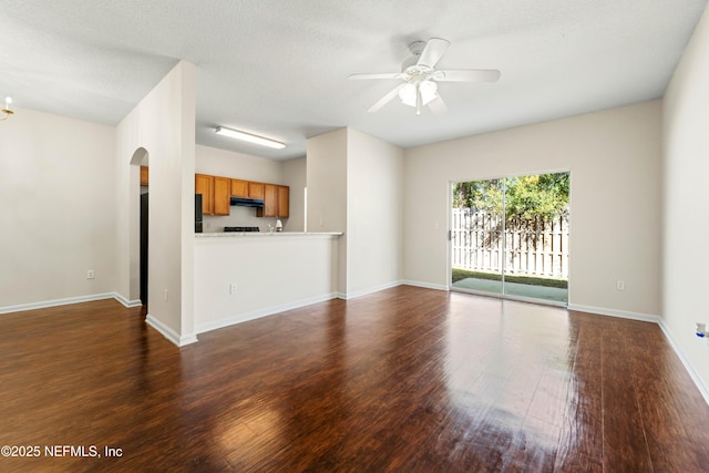 unfurnished living room with baseboards, arched walkways, wood finished floors, and a ceiling fan