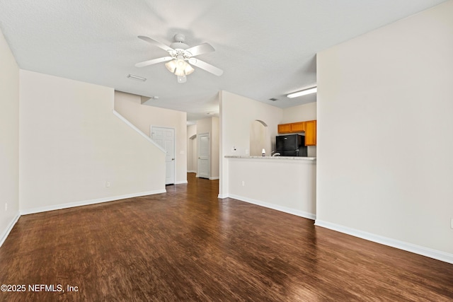 unfurnished living room featuring visible vents, baseboards, ceiling fan, and wood finished floors