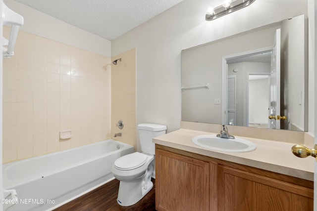 bathroom with vanity, wood finished floors, a textured ceiling, bathing tub / shower combination, and toilet