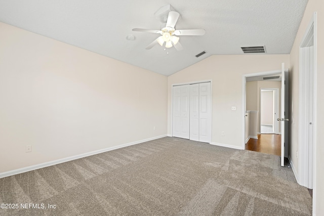 unfurnished bedroom featuring visible vents, lofted ceiling, carpet, and a closet