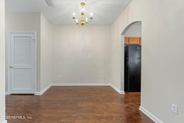 unfurnished dining area featuring visible vents, arched walkways, dark wood-style flooring, and a chandelier