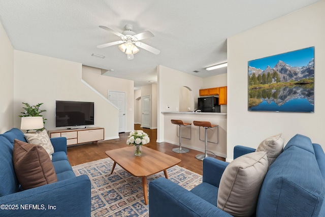 living room featuring baseboards, wood finished floors, visible vents, and ceiling fan