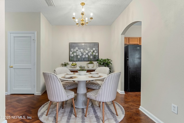 dining room with visible vents, a notable chandelier, a textured ceiling, arched walkways, and baseboards