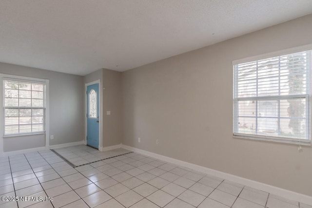 empty room featuring light tile patterned floors and baseboards