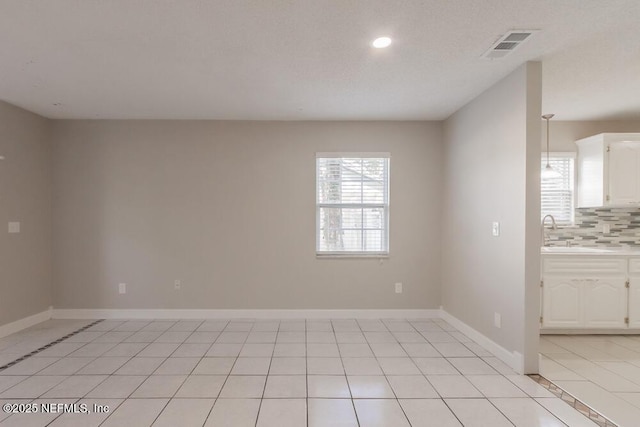 unfurnished room with plenty of natural light, light tile patterned flooring, and baseboards