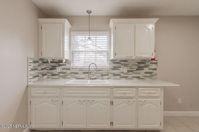 kitchen with tasteful backsplash, white cabinets, light countertops, and a sink