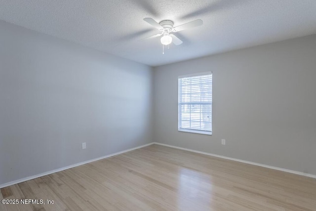 spare room with ceiling fan, baseboards, a textured ceiling, and light wood-style flooring