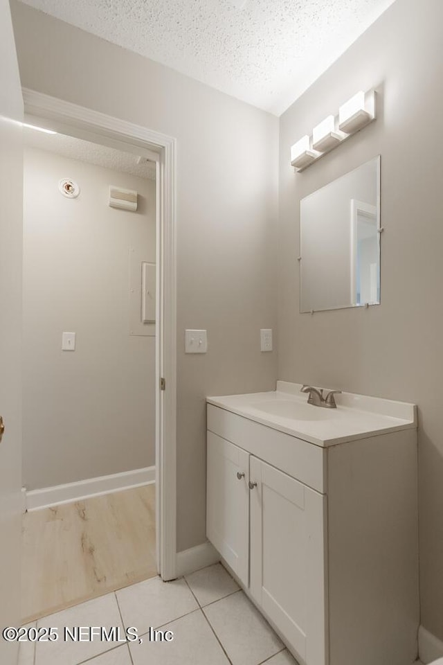 bathroom featuring tile patterned floors, baseboards, a textured ceiling, and vanity