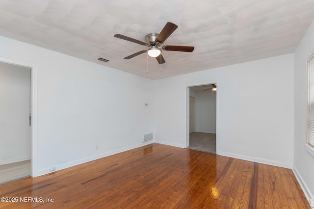 unfurnished room featuring visible vents, baseboards, and wood finished floors