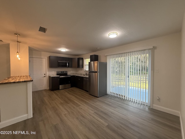 kitchen featuring pendant lighting, a sink, dark wood finished floors, stainless steel appliances, and baseboards