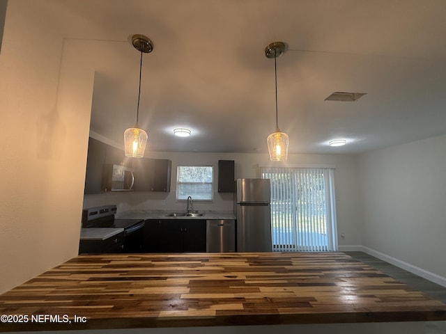 kitchen with dark wood-style flooring, a sink, light countertops, appliances with stainless steel finishes, and decorative light fixtures