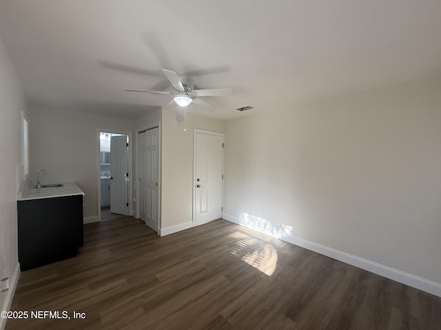 unfurnished bedroom with dark wood-style floors, visible vents, baseboards, a sink, and a closet