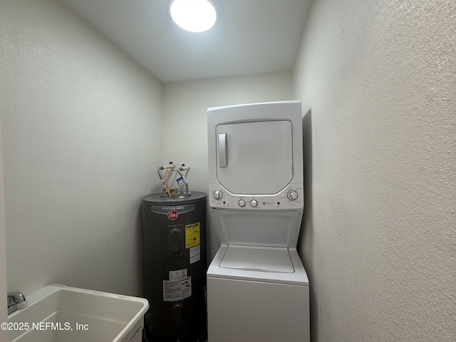 clothes washing area with laundry area, a sink, electric water heater, stacked washer / dryer, and a textured wall