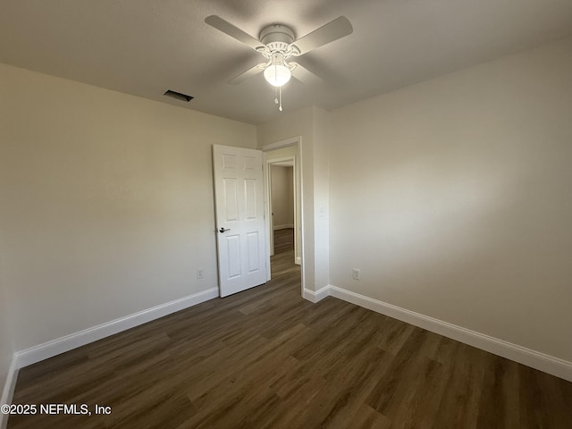 empty room featuring visible vents, baseboards, ceiling fan, and dark wood-style flooring