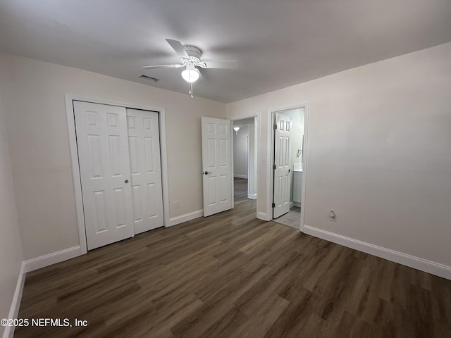 unfurnished bedroom featuring baseboards, visible vents, and dark wood-style flooring