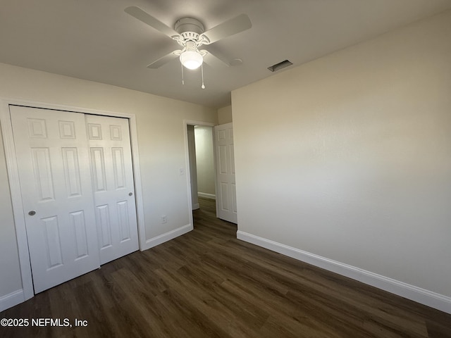 unfurnished bedroom featuring baseboards, visible vents, dark wood-style flooring, ceiling fan, and a closet