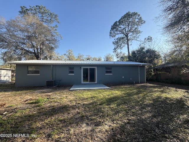 rear view of property featuring metal roof, a lawn, and cooling unit