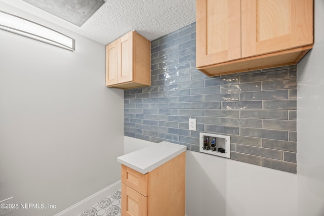 clothes washing area featuring cabinet space, a textured ceiling, hookup for a washing machine, and baseboards