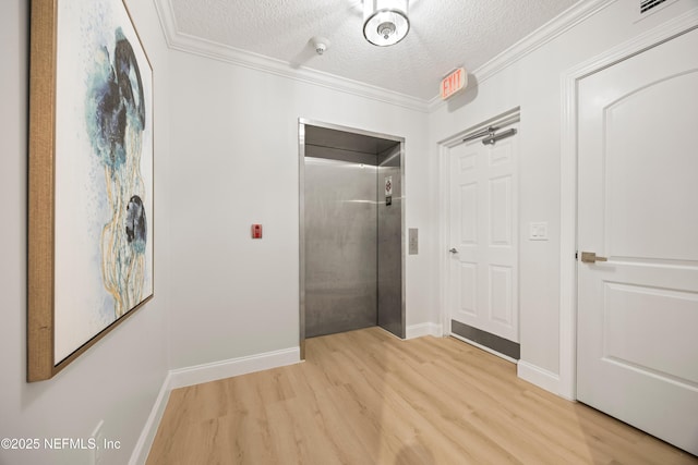 corridor featuring crown molding, light wood-style flooring, elevator, and a textured ceiling