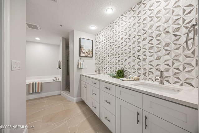 full bathroom with visible vents, a garden tub, a stall shower, a textured ceiling, and a sink