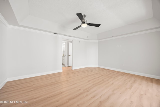 empty room featuring baseboards, a raised ceiling, light wood-style floors, and ceiling fan