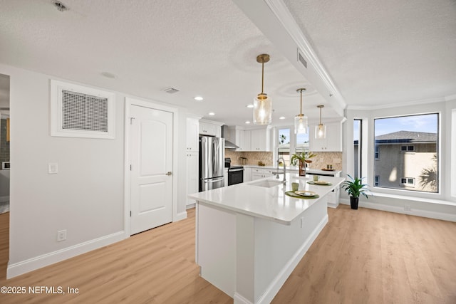 kitchen with appliances with stainless steel finishes, white cabinetry, light wood-style floors, and a sink