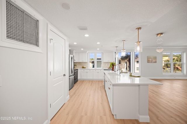 kitchen with light wood-type flooring, a sink, tasteful backsplash, freestanding refrigerator, and light countertops