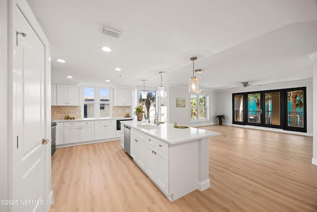 kitchen with tasteful backsplash, visible vents, light countertops, light wood-type flooring, and a sink