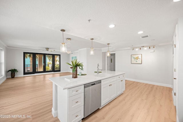 kitchen with a sink, stainless steel dishwasher, open floor plan, light wood-style floors, and white cabinets