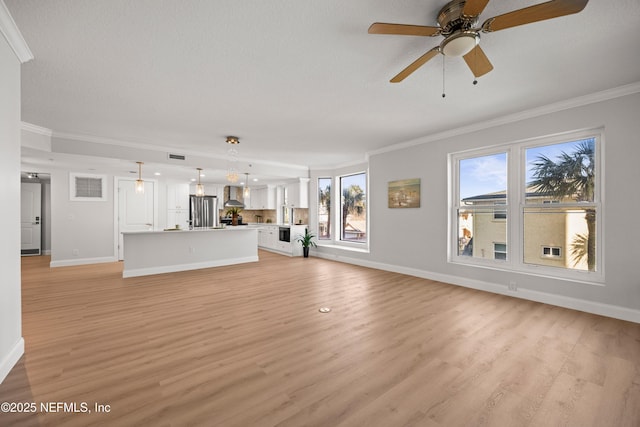 unfurnished living room featuring light wood-type flooring, baseboards, and crown molding