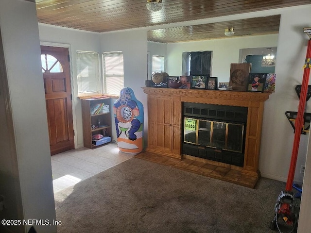 living room featuring a glass covered fireplace, light tile patterned floors, wood ceiling, and light carpet