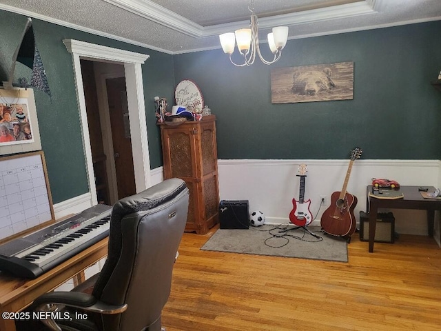 office area with wood finished floors, a wainscoted wall, a tray ceiling, ornamental molding, and a chandelier