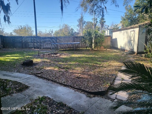 view of yard featuring a storage unit, an outdoor structure, a fenced backyard, and a trampoline