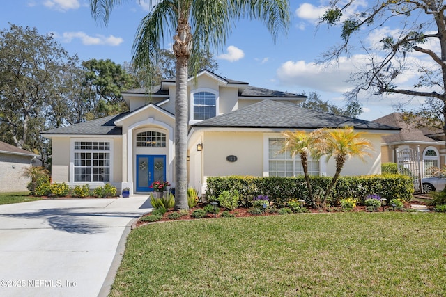 view of front of property featuring roof with shingles, driveway, stucco siding, a front lawn, and french doors