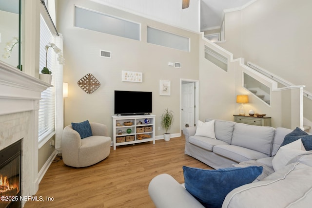 living area with visible vents, baseboards, a warm lit fireplace, and light wood finished floors