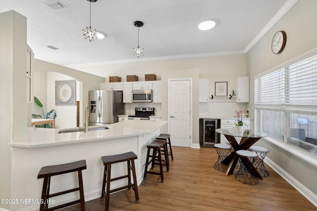 kitchen featuring visible vents, a breakfast bar, beverage cooler, a sink, and stainless steel appliances