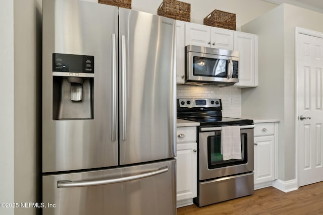 kitchen featuring decorative backsplash, white cabinets, stainless steel appliances, and light countertops