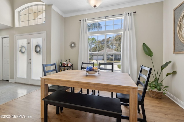 dining room with crown molding, light wood-style flooring, and baseboards