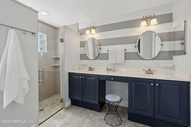 full bathroom featuring a textured ceiling, double vanity, a stall shower, and a sink