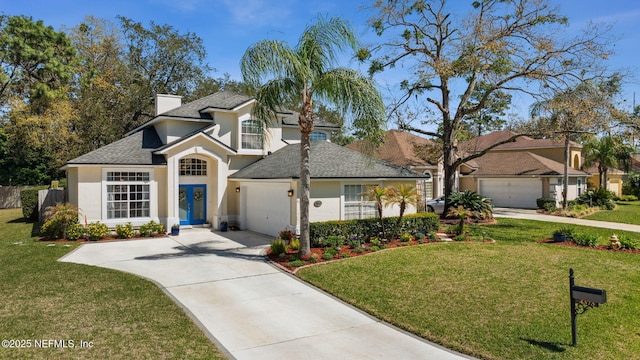 traditional-style house featuring concrete driveway, an attached garage, a front yard, and stucco siding