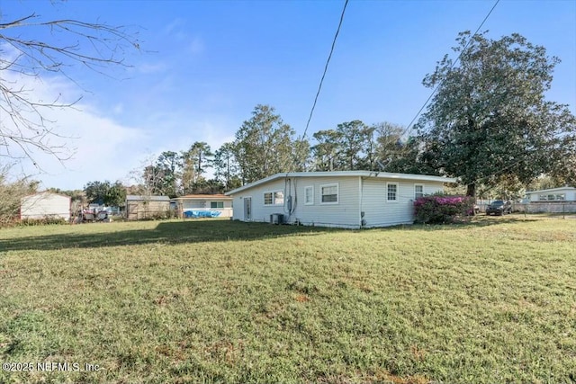 exterior space with central AC unit and a lawn