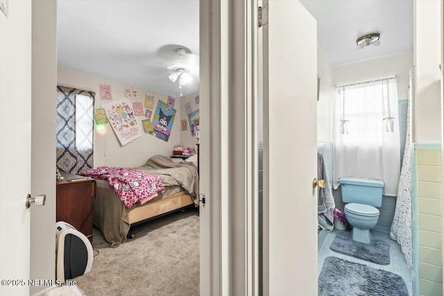 bedroom featuring tile walls, ensuite bathroom, and carpet