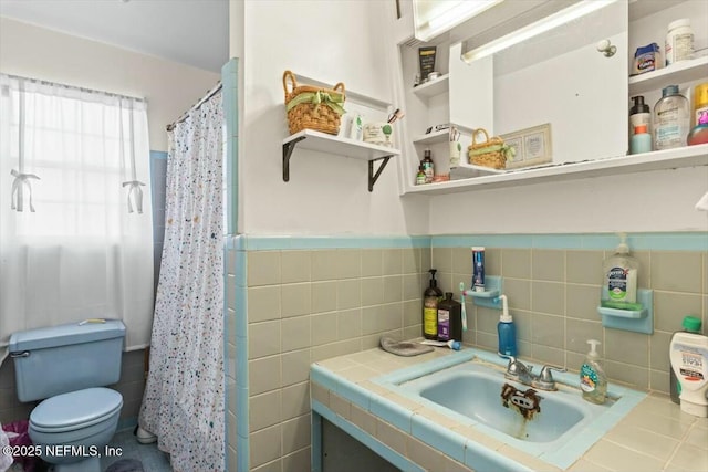 full bathroom featuring a wainscoted wall, toilet, curtained shower, tile walls, and vanity